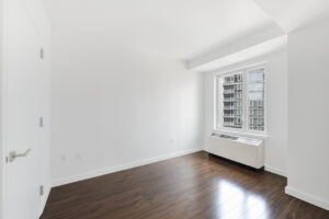 Interior unit bedroom,wood floorrs, ac unit near window, white walls, door opposite of window.