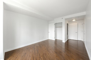 Interior Unit Bedroom, wood floors, white walls, closet next to entrance.